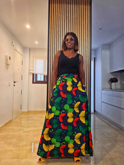 Woman wearing FLORES Cotton Print Maxi Skirt with vibrant floral design in a modern kitchen setting.